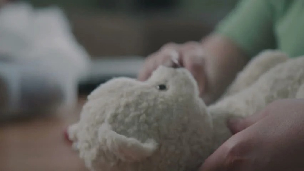 Person hand-stitching a soft white plush toy, showing craftsmanship and attention to detail in toy production.