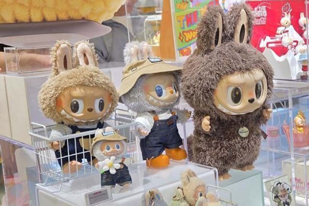 Display of Pop Mart collectible bunny-eared figures in fluffy costumes and denim overalls, arranged on clear stands inside a brightly lit store.