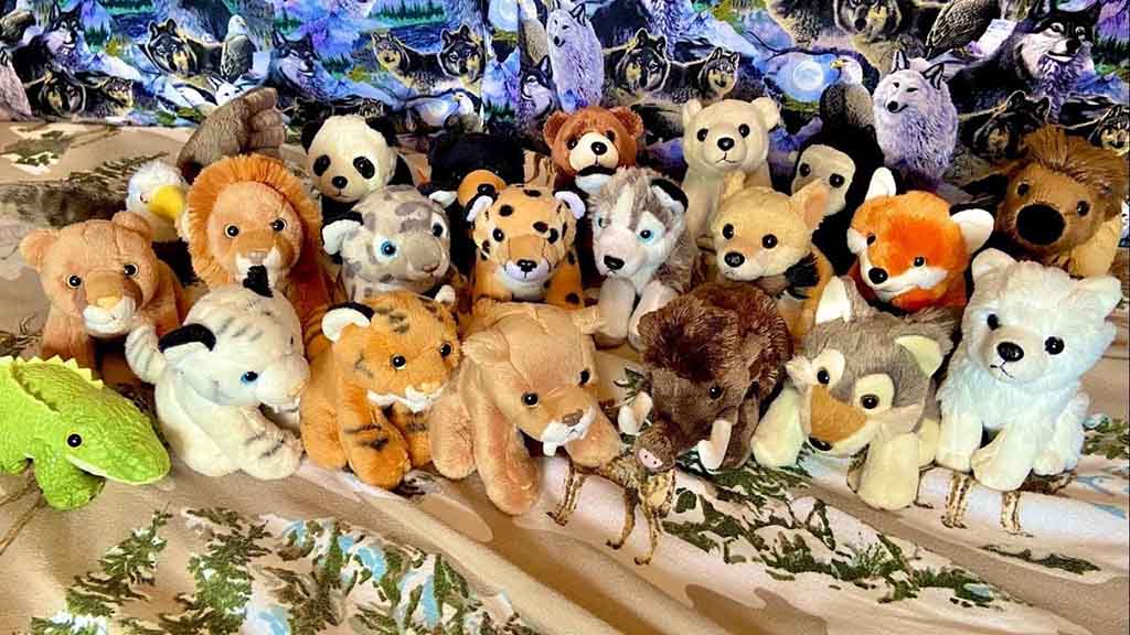 Group of Wild Republic plush animals including lions, foxes, wolves, pandas, and other wildlife displayed together on a patterned blanket.