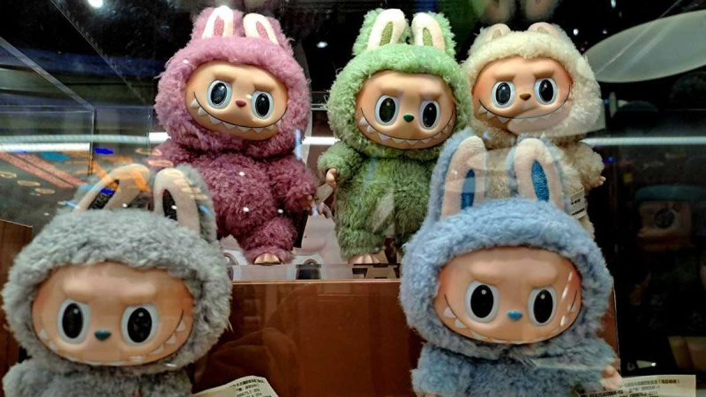 Colorful Labubu figures in fuzzy bunny costumes displayed in a showcase, representing popular blind box toy collectibles.
