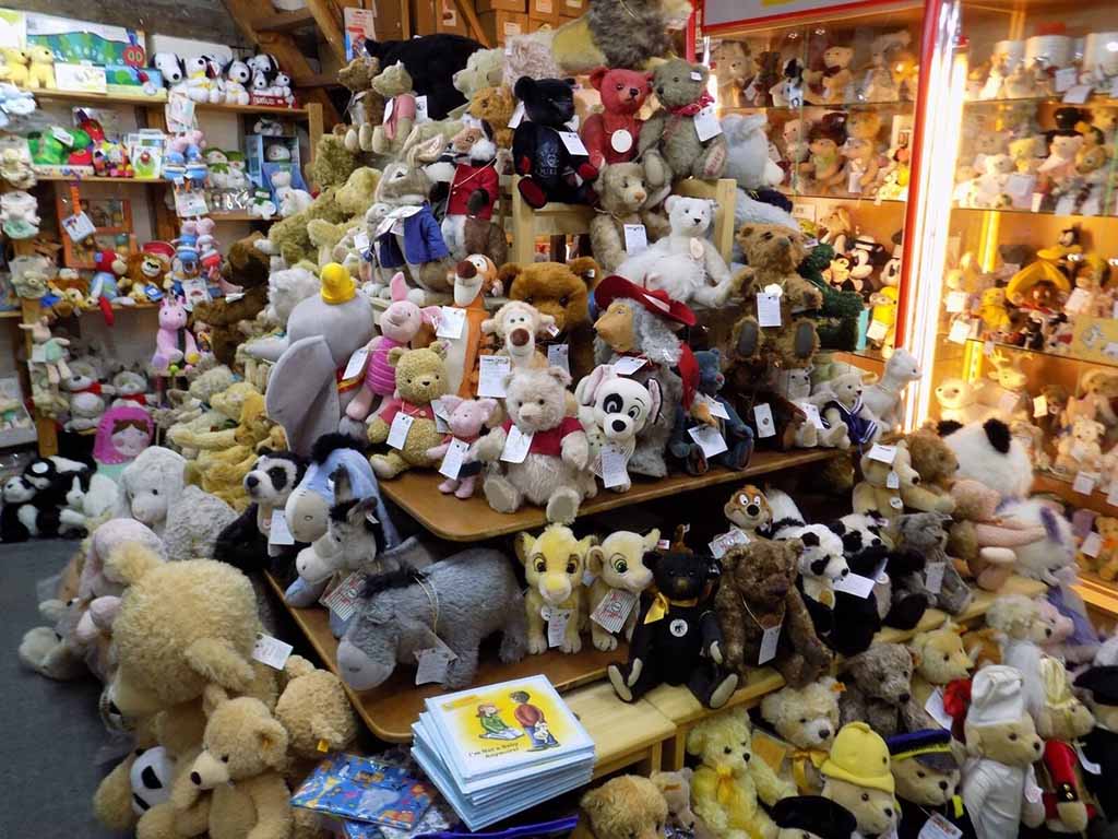 A toy store filled with shelves and tables stacked with various stuffed animals including bears, dogs, rabbits, and other plush characters.