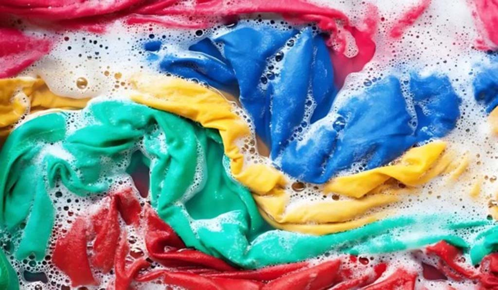 Multicolored fabric pieces soaked in soapy water during a color fastness test to check dye stability for plush materials.