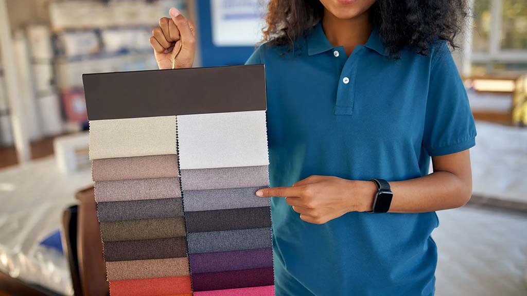 A woman holding a large fabric swatch board displaying multiple color options in a showroom.
