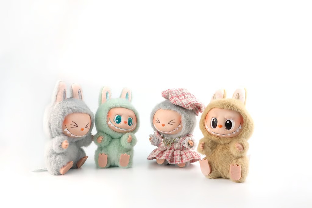 Four Labubu collectible plush figures wearing soft bunny costumes in gray, mint green, and beige, with one dressed in a plaid outfit, arranged on a white background.