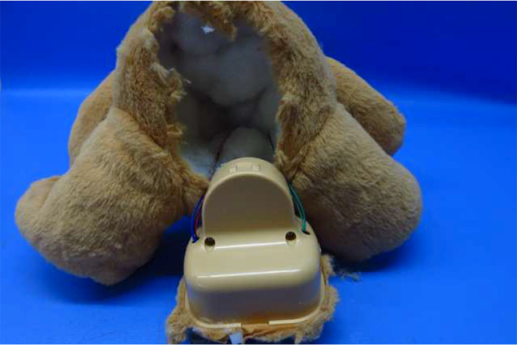 A brown plush toy opened at the back to reveal an internal plastic sound module and wiring, showing how voice boxes are installed inside stuffed animals.