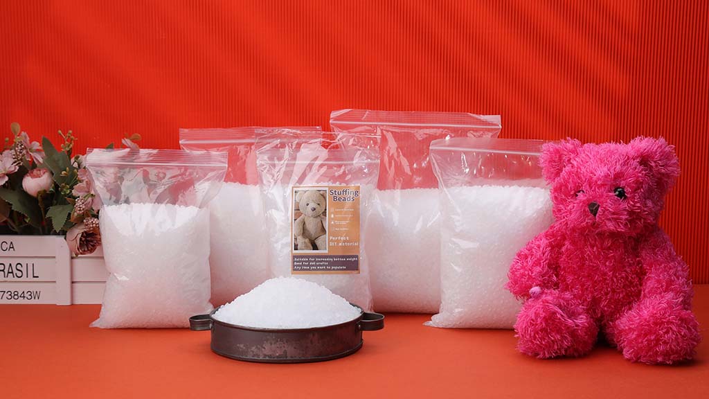 Bags of white stuffing beads displayed beside a pink teddy bear, showing materials commonly used to fill and shape plush toys.