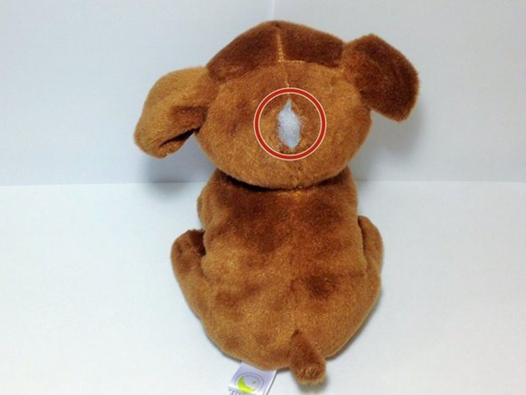 Brown stuffed dog toy with a tear on its back showing white stuffing