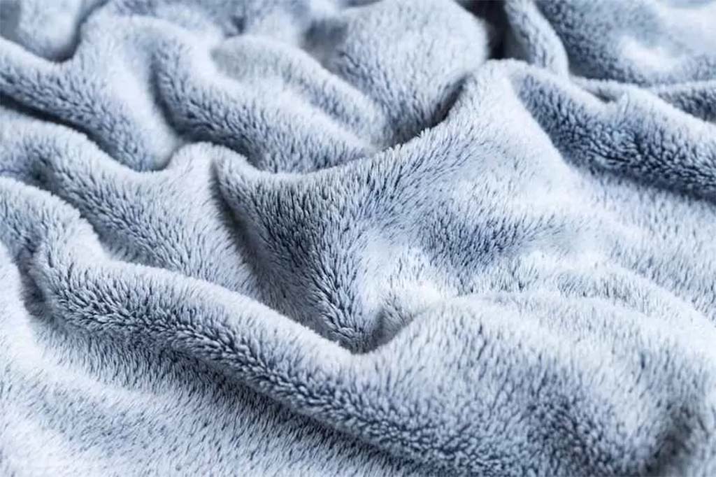 Close-up view of soft grey plush fabric with long, smooth fibers and gentle folds, showing its fluffy texture for plush toys.