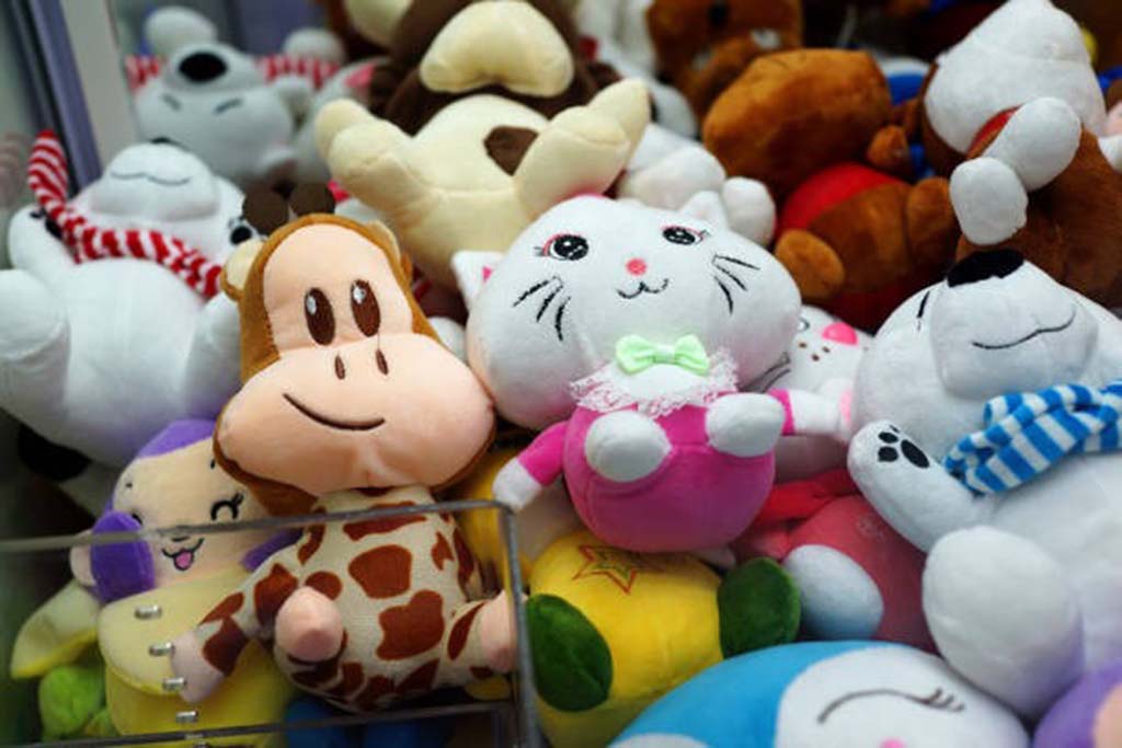 A mix of colorful plush toys, including a giraffe, cat, bear, and other characters, piled inside a claw machine.