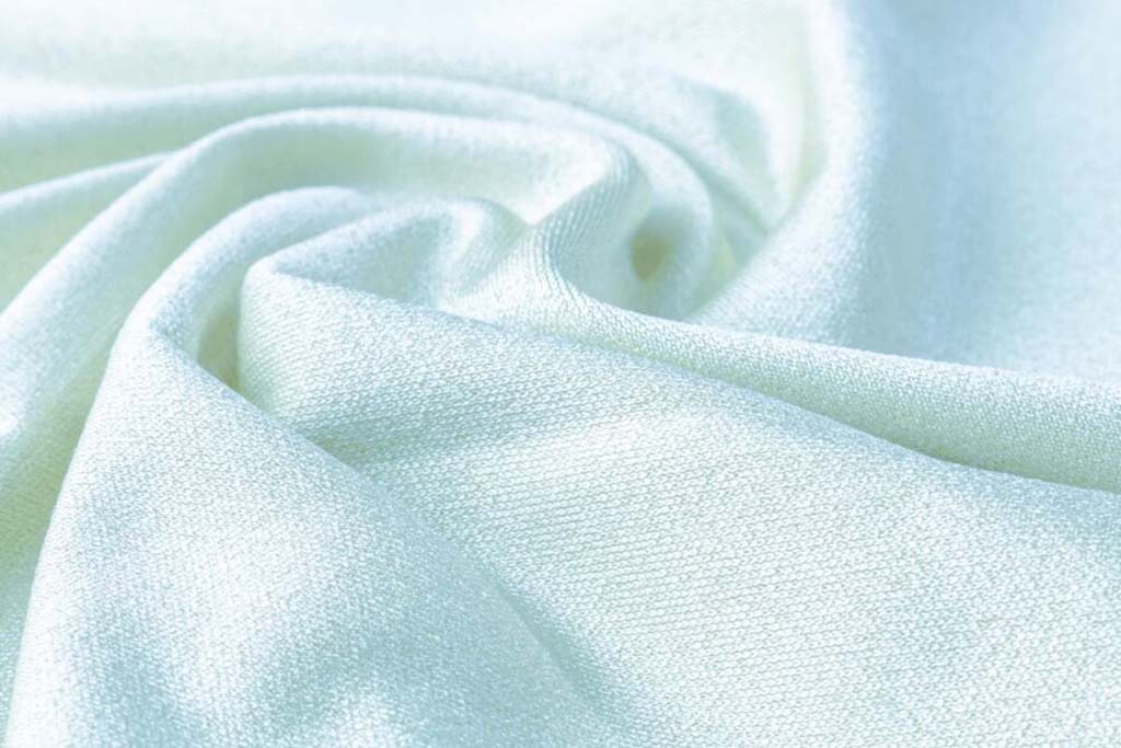 Smooth white microfiber fabric with soft texture and gentle folds, commonly used for plush toy surfaces, cushions, and apparel lining.