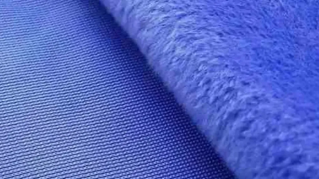 Close-up of blue plush fabric showing soft fuzzy surface layered over tightly woven backing