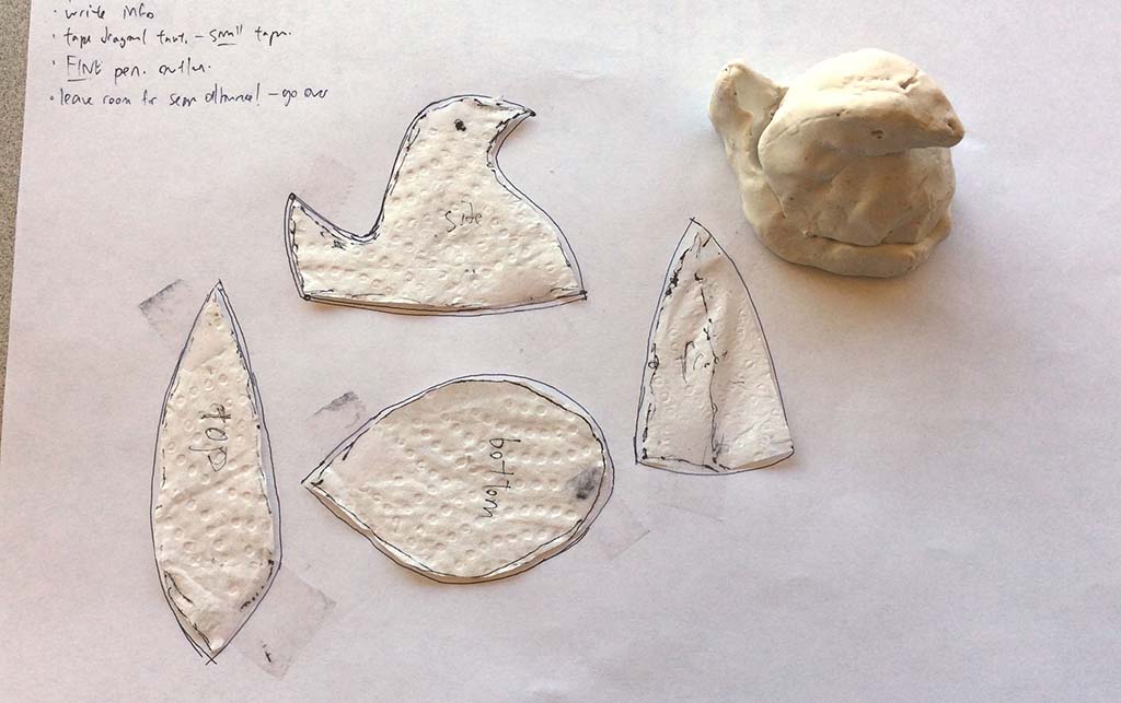 Hand-drawn plush toy pattern pieces and a clay model displayed on paper