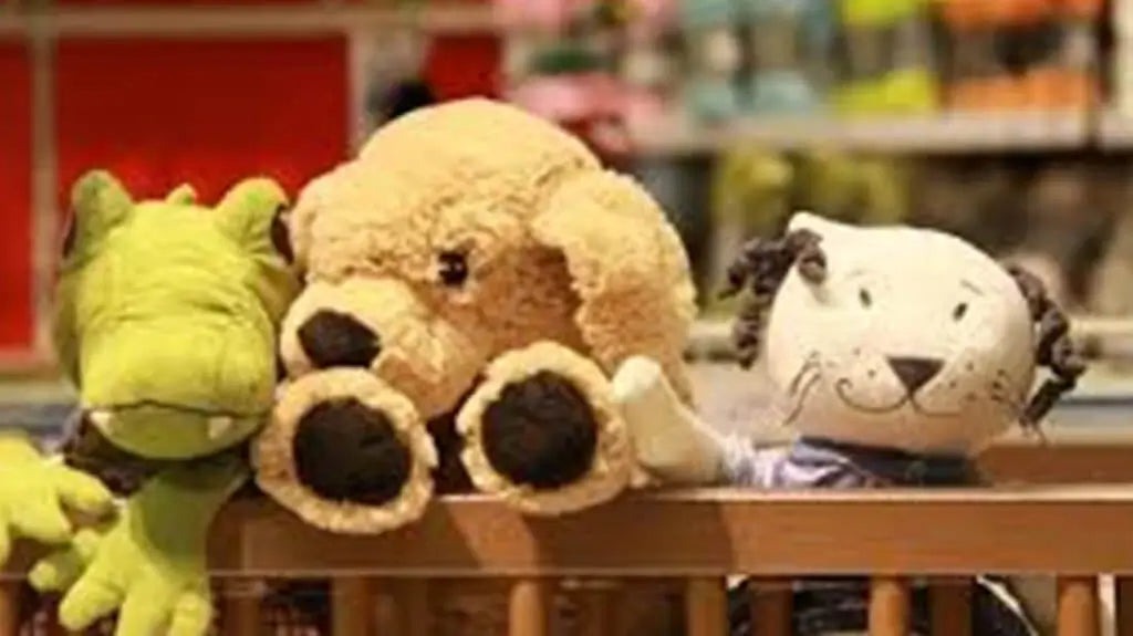 Three soft plush toys—a green crocodile, a beige bear, and a white cat—sitting together on a store shelf, showing different character designs and textures.