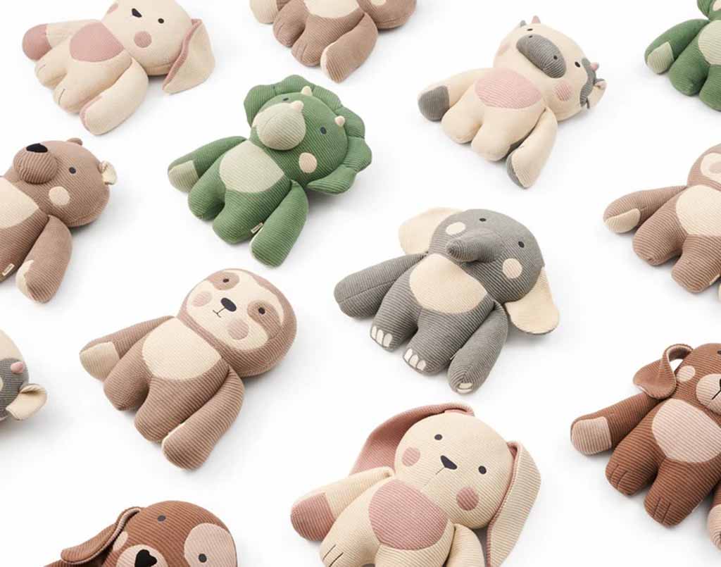 Assorted knitted plush animals—including elephants, dogs, sloths, and dinosaurs—arranged in a neat pattern on a white background.