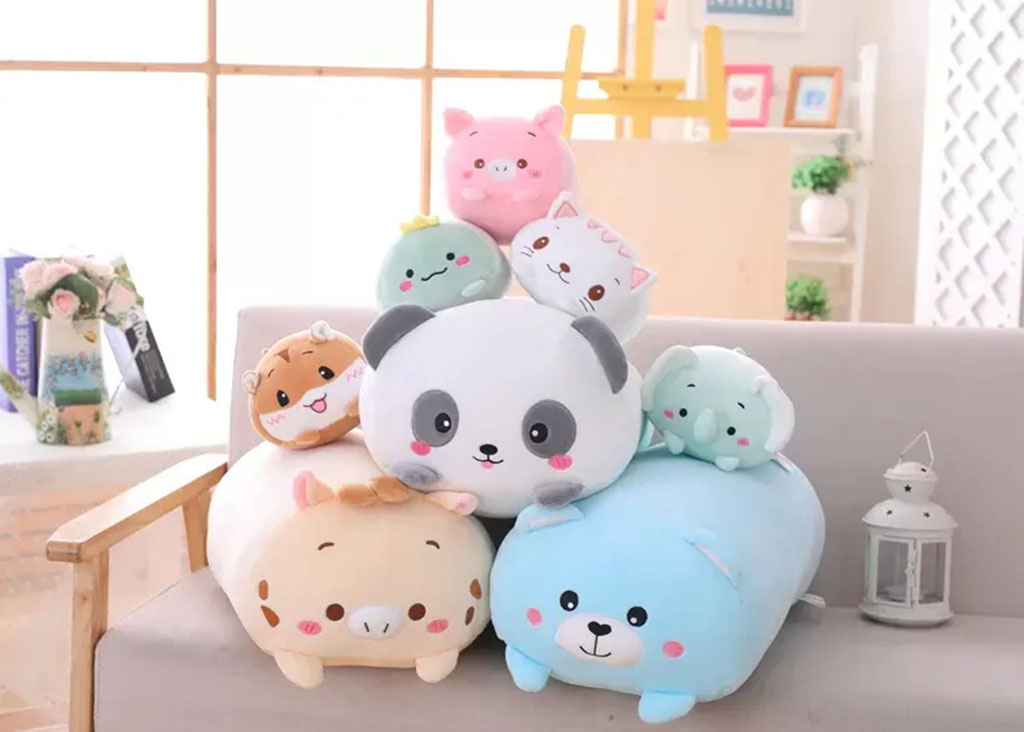 A colorful stack of round animal plush toys, including a panda, cat, pig, bear, hamster, elephant, and more, arranged on a sofa in a bright, cozy living room.