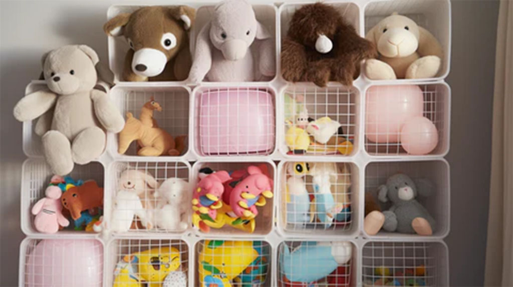 A collection of plush toys of various sizes and colors neatly arranged inside a modular white plastic grid storage shelf.