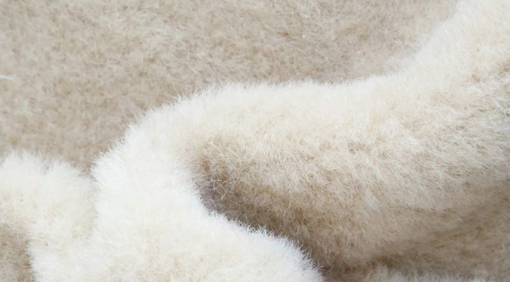 Close-up of cream-colored short-pile teddy fur fabric with a soft, fluffy texture, commonly used for plush toys, teddy bears, and baby-safe stuffed animals.