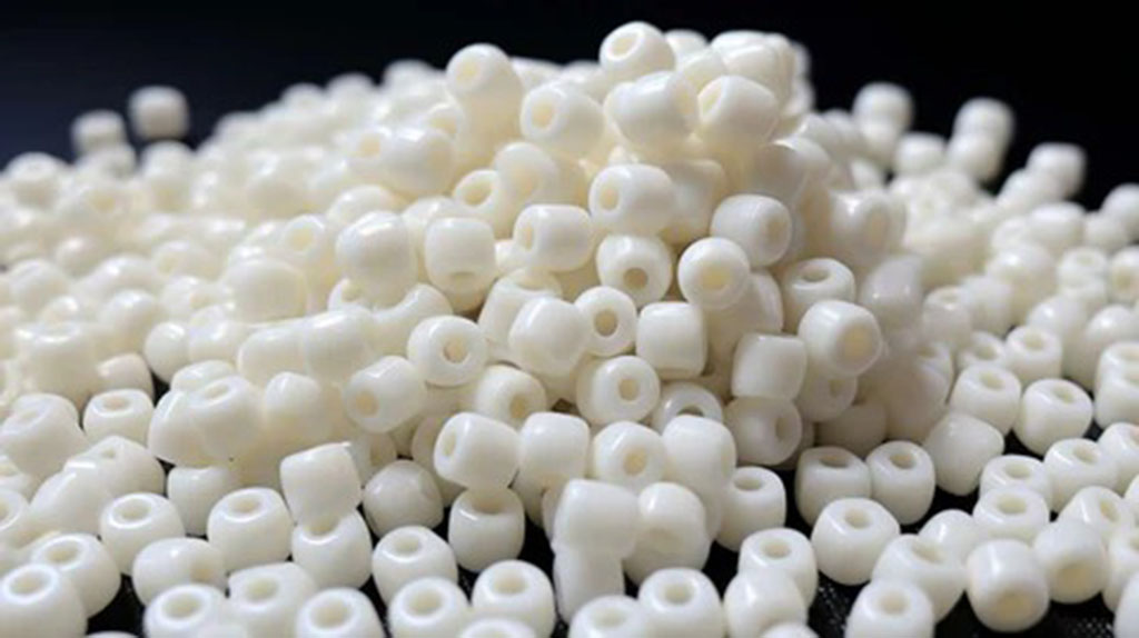 White cylindrical plastic pellets with center holes piled together, commonly used as stuffing or weighting material for toys.