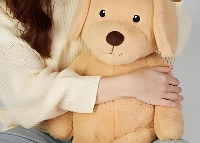 A woman gently hugs a large beige plush dog toy while sitting, showing comfort and closeness.