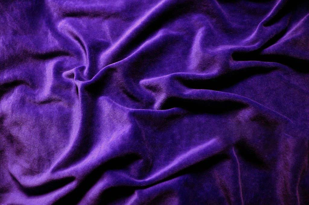 Close-up of deep purple plush velvet fabric with soft texture and natural folds, commonly used for high-end plush toys, apparel, and luxury textile applications.