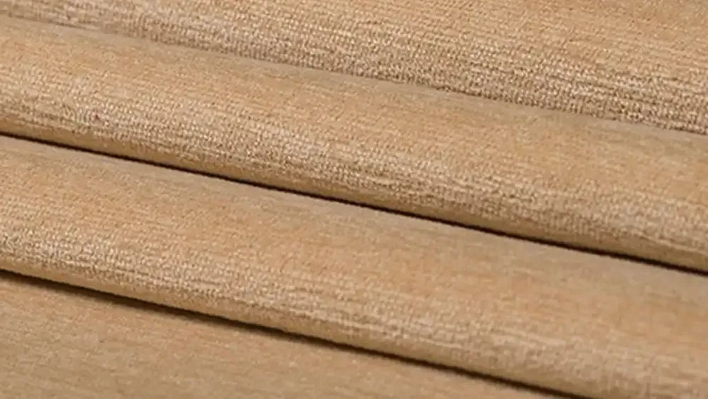  Close-up of folded beige chenille fabric with a soft, velvety surface and subtle sheen, often used for plush toys, upholstery, and home décor.