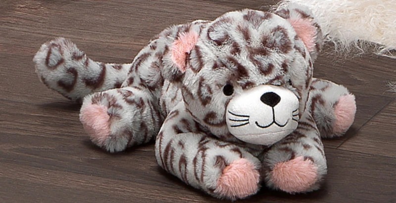 A soft grey leopard plush toy with pink ears, paws, and a friendly embroidered face resting on a wooden floor.