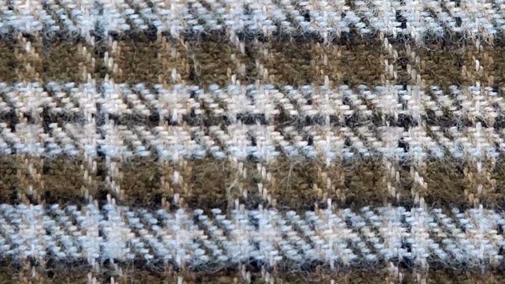  Close-up of soft plaid flannel fabric in brown, gray, and cream tones, showing fuzzy texture and woven check pattern ideal for plush toys and apparel.