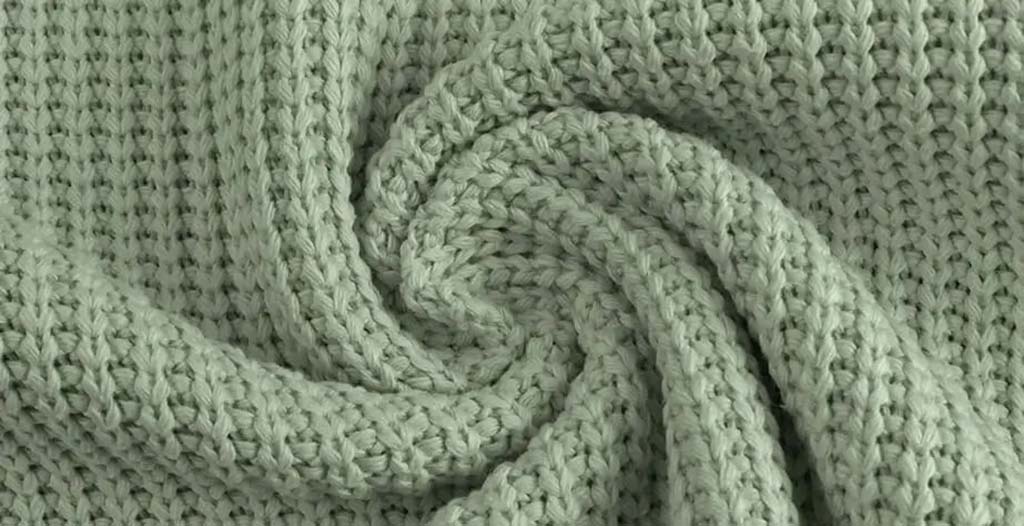 Close-up of light green knitted fabric with a waffle texture, ideal for making cozy and soft plush toys.