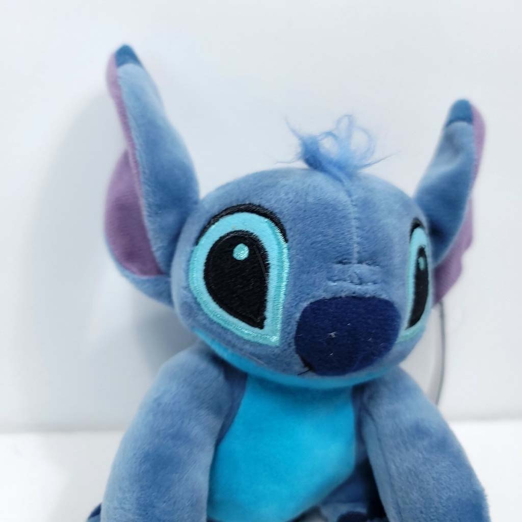Blue alien-inspired plush toy with large embroidered eyes, big ears, and soft velvety fabric, sitting against a white background.