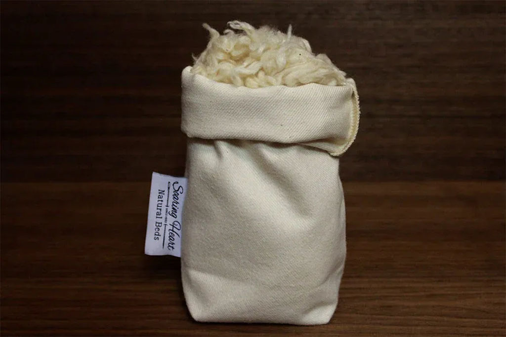 Small cotton bag filled with natural kapok fiber, showing eco-friendly stuffing material commonly used in plush toys, pillows, and handmade crafts.