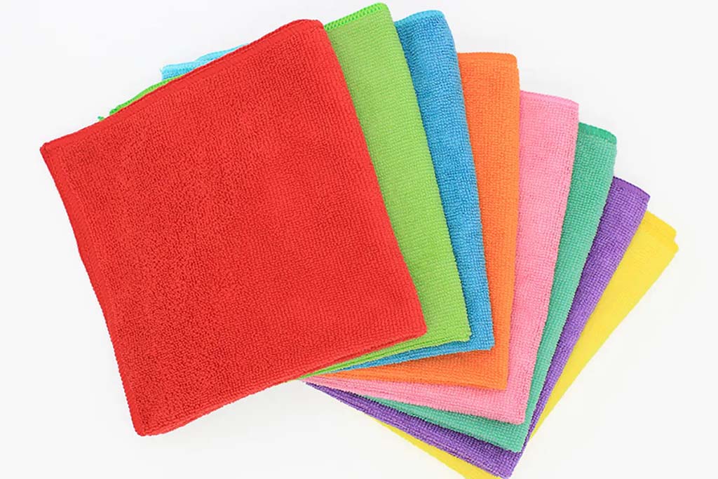 Assorted microfiber fabric swatches in bright colors arranged in a fan layout, showing smooth texture and vibrant tones.