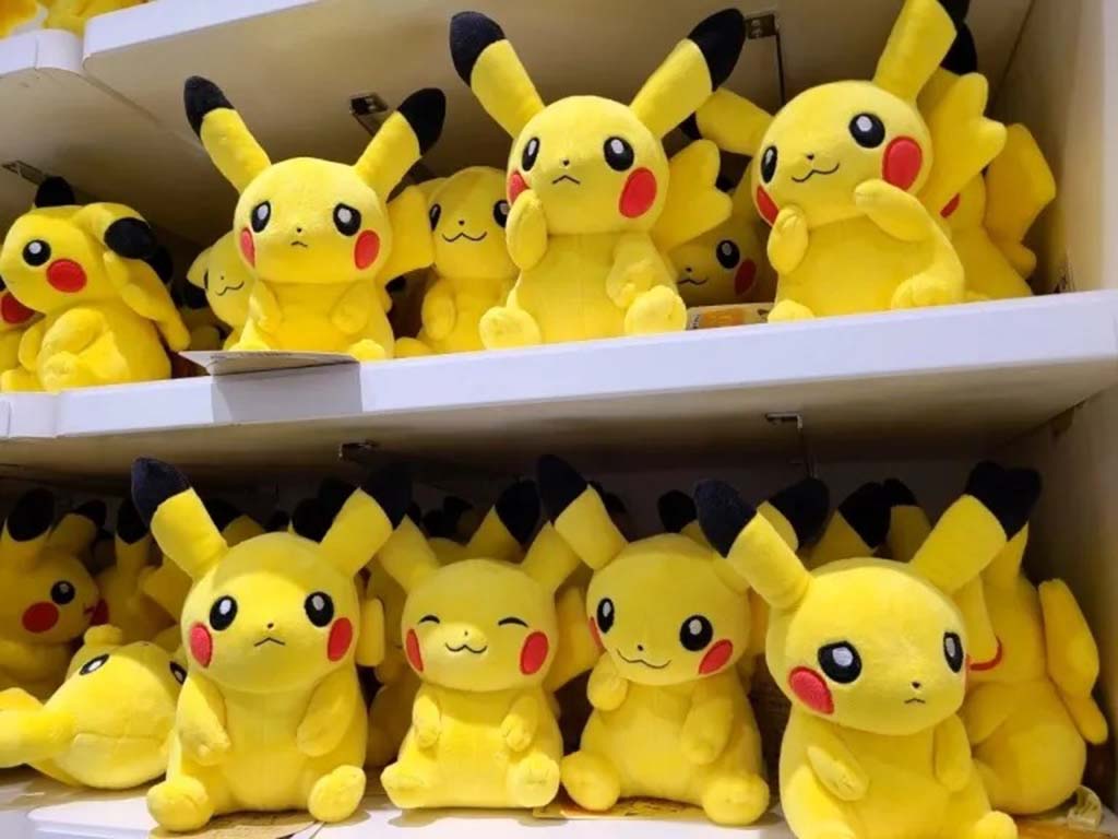 Multiple Pikachu plush toys arranged on store shelves, featuring different facial expressions and bright yellow fabric.