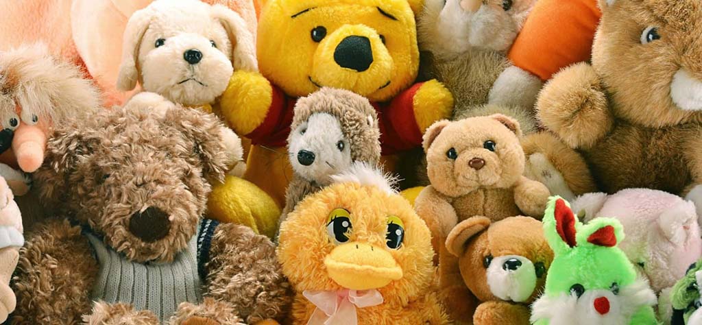 A large assortment of colorful plush toys including teddy bears, ducks, dogs, and other stuffed animals grouped together in a display.