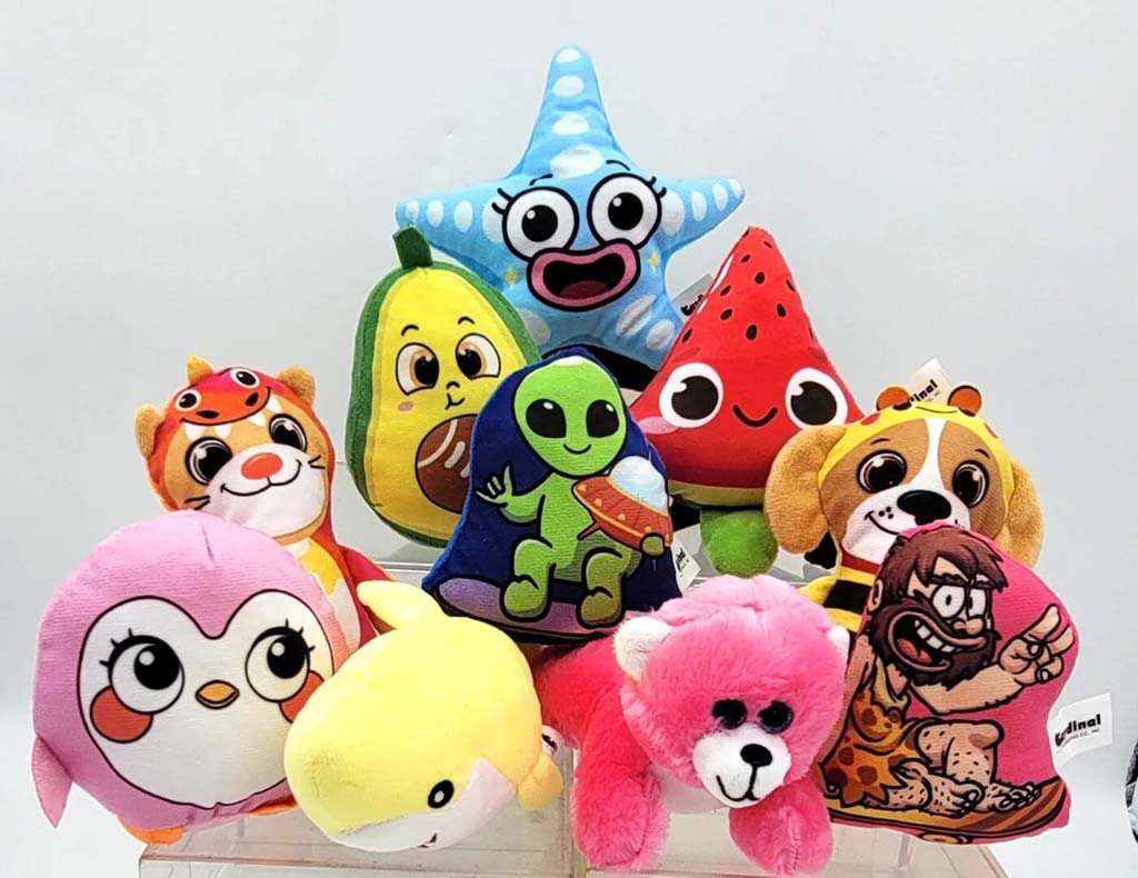 A group of brightly colored plush toys including animals, fruits, and cartoon characters arranged together on a clear display stand.