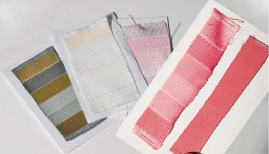 Assorted fabric test strips showing color fastness results, including gradient fading and multi-colored samples displayed on white cards.