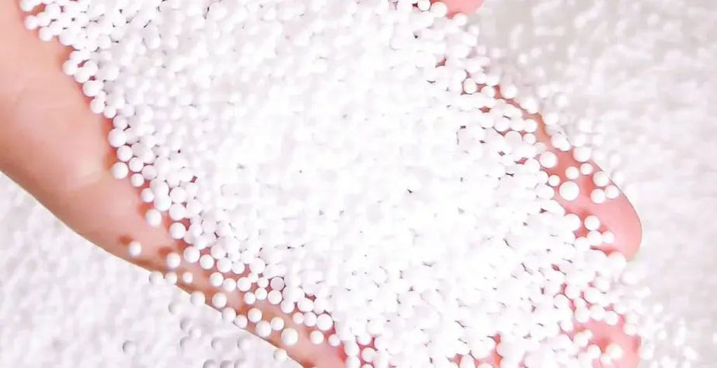 Hand holding soft white microbeads used as plush toy filling, showing their smooth texture, lightweight feel, and uniform bead size for premium stuffed animal stuffing.