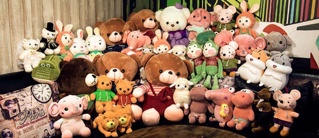 A big group of assorted plush toys including bears, rabbits, pigs, frogs, and other characters arranged together on a sofa.