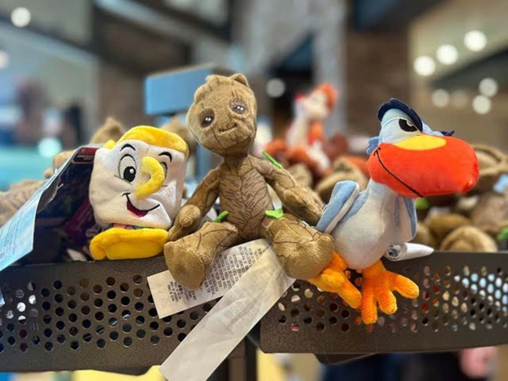 Close-up of small Disney plush toys including Chip from “Beauty and the Beast,” Groot, and Zazu from “The Lion King” arranged on a store shelf.