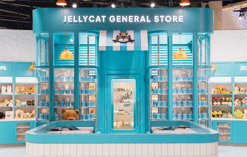 Bright turquoise Jellycat retail display featuring shelves of plush toys and themed products inside a stylized general-store setup.