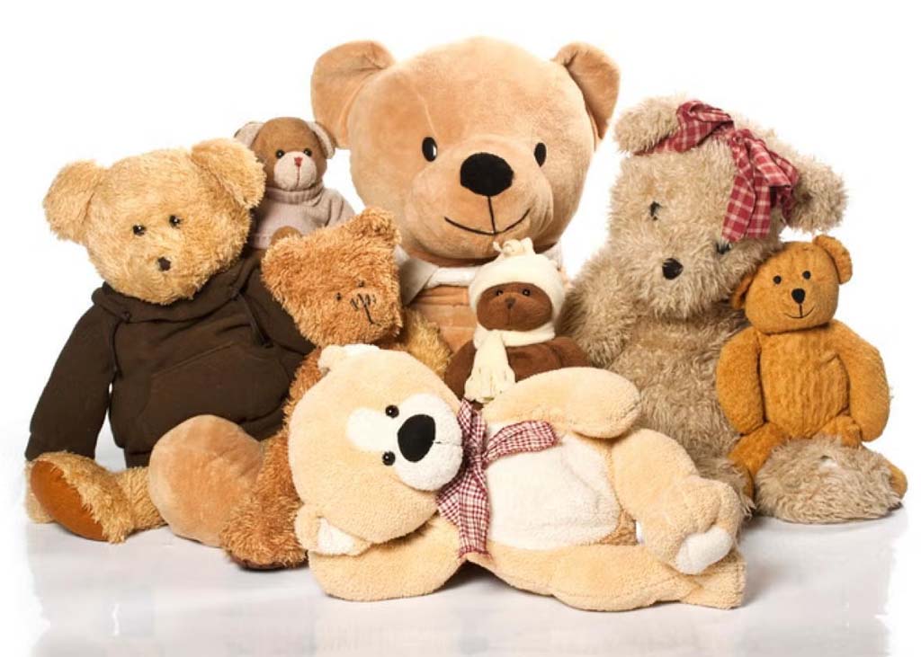 A collection of soft teddy bears in various sizes and shades of brown posed together against a white background.