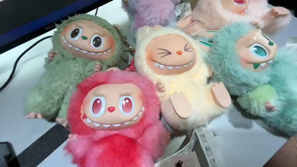 A group of colorful Labubu plush dolls with expressive faces and fluffy textured bodies, displayed on a table during sample review.