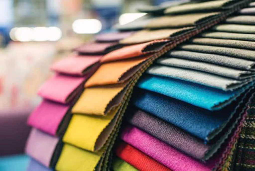 A stack of colorful fabric swatches arranged in overlapping layers, showcasing various textures and shades used in plush toy manufacturing.
