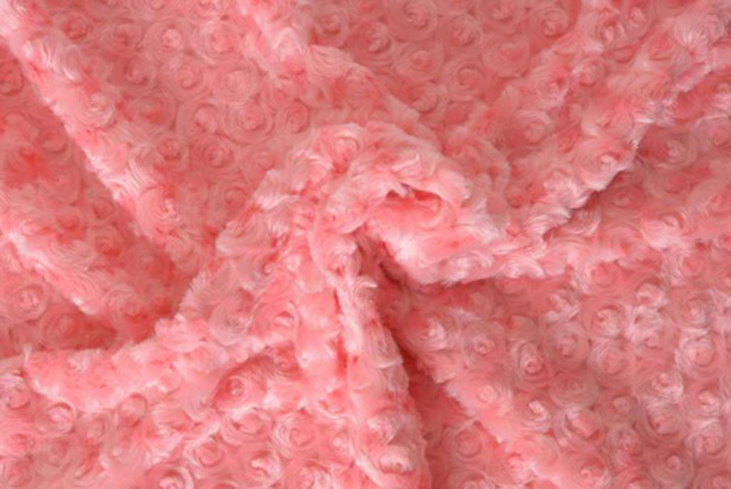 Close-up of soft pink rose swirl plush fabric showing fluffy texture and embossed spiral patterns used in stuffed toy making.