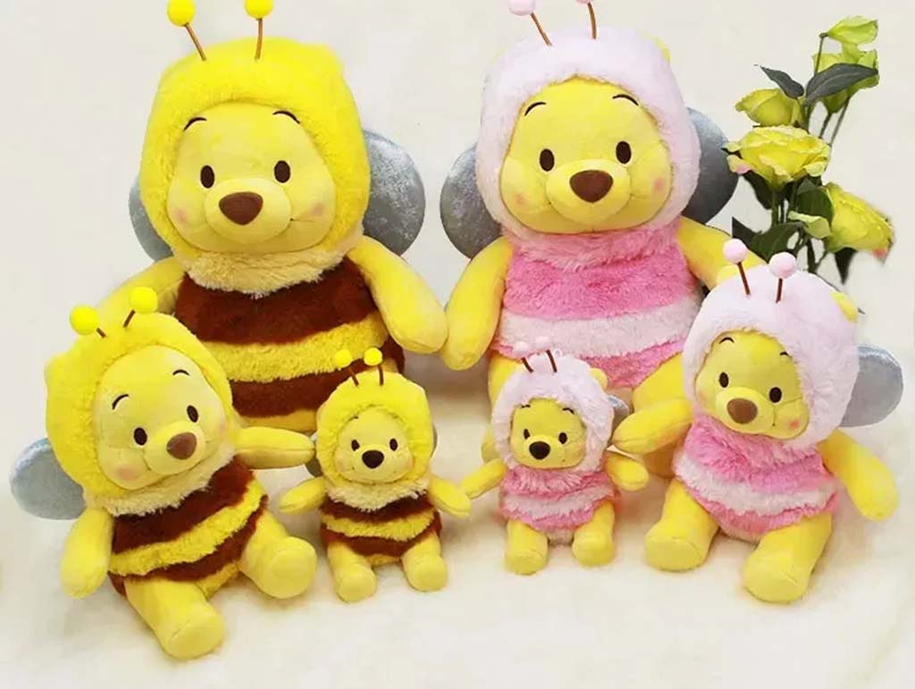 Group of Winnie the Pooh plush toys dressed in bee costumes, with yellow and pink striped outfits, arranged in pairs of large and small sizes.