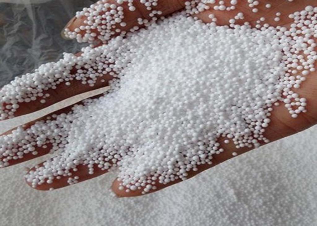  Hand holding small white expanded polystyrene beads, a lightweight and flexible stuffing option used in bean bag and plush toy production.