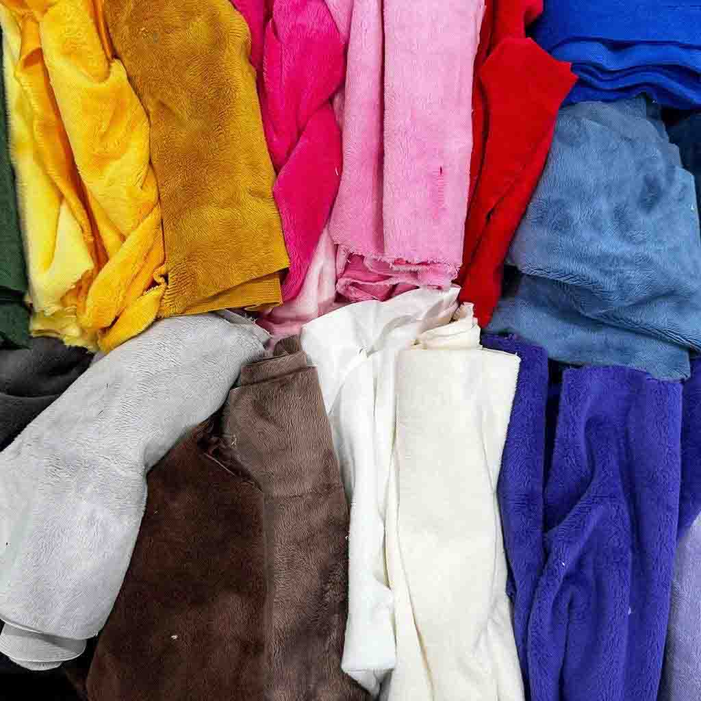 Assorted colorful plush fabrics in various textures arranged in a pile.