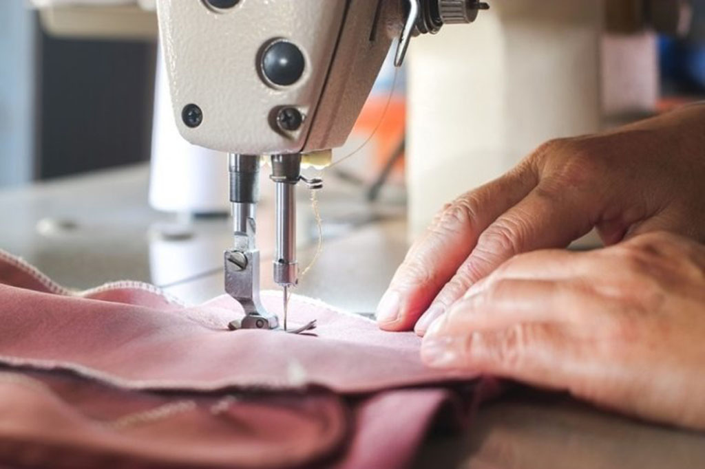 Close-up of a worker sewing fabric with an industrial sewing machine, ensuring smooth seams and durability for plush toy manufacturing.