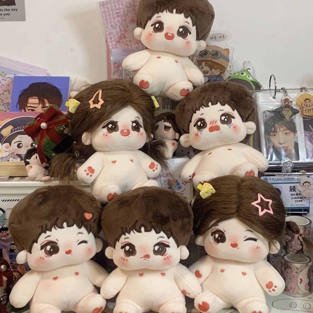 A collection of adorable baby-style plush dolls with big eyes, rosy cheeks, and soft brown hair, some decorated with colorful hair clips and arranged in a display.