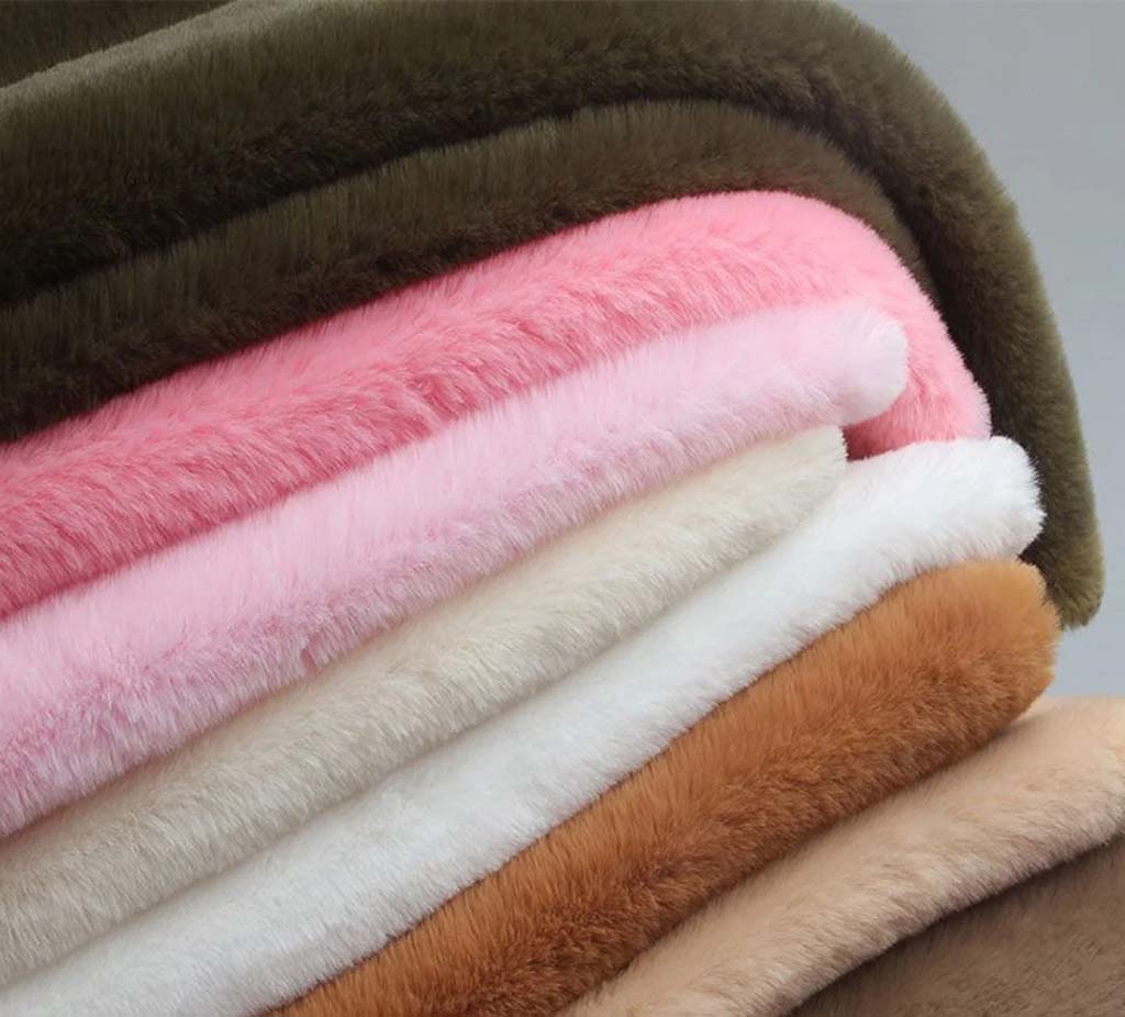 Stack of soft, colorful plush fabrics in various shades, showing fluffy texture commonly used for making stuffed animals and plush toys.
