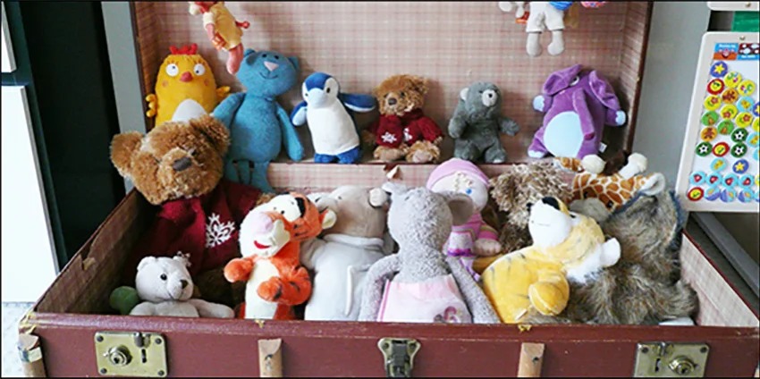 Open vintage trunk filled with assorted stuffed animals including bears, penguins, rabbits, and other plush toys neatly arranged inside.